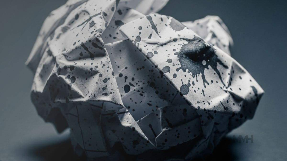 Crumpled paper splattered with ink, symbolising how overwhelming demands and mental pressure can lead to emotional stress.