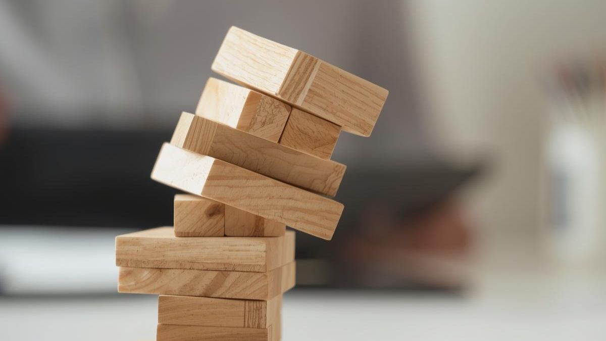 A tower of wooden blocks leaning over, representing the impact of sleep deprivation on life stability.