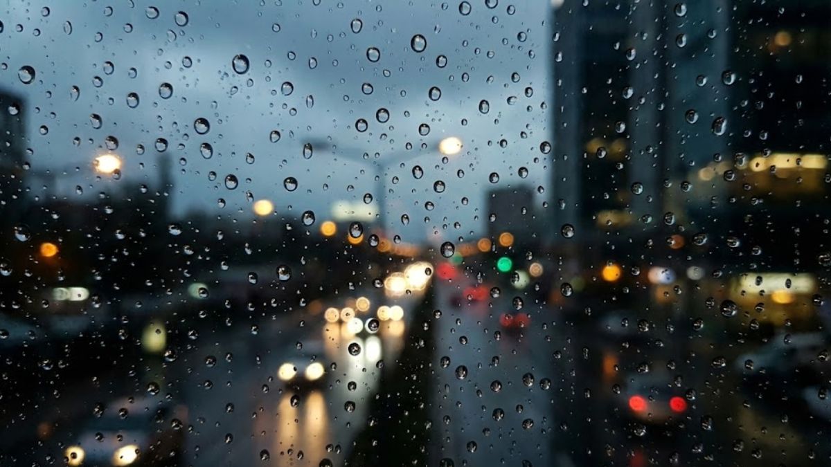 Raindrops on a window pane blurring the city lights outside, representing mental confusion and hangxiety.