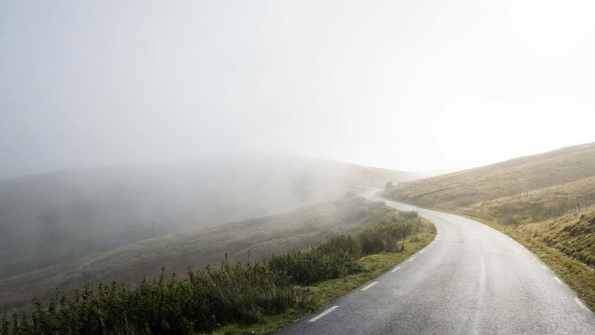 Morning fog lifting from a road to reveal the path ahead.