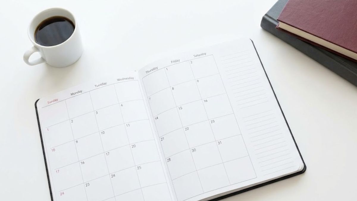 A clean white desk with an open planner, a cup of coffee, and books, representing the daily schedule and the importance of reclaiming time.