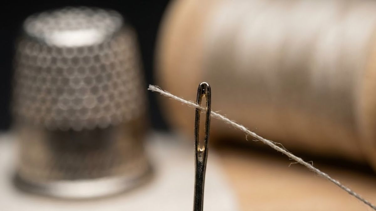 Extreme close up of a thread in a needle eye to demonstrate how fine the tools are.