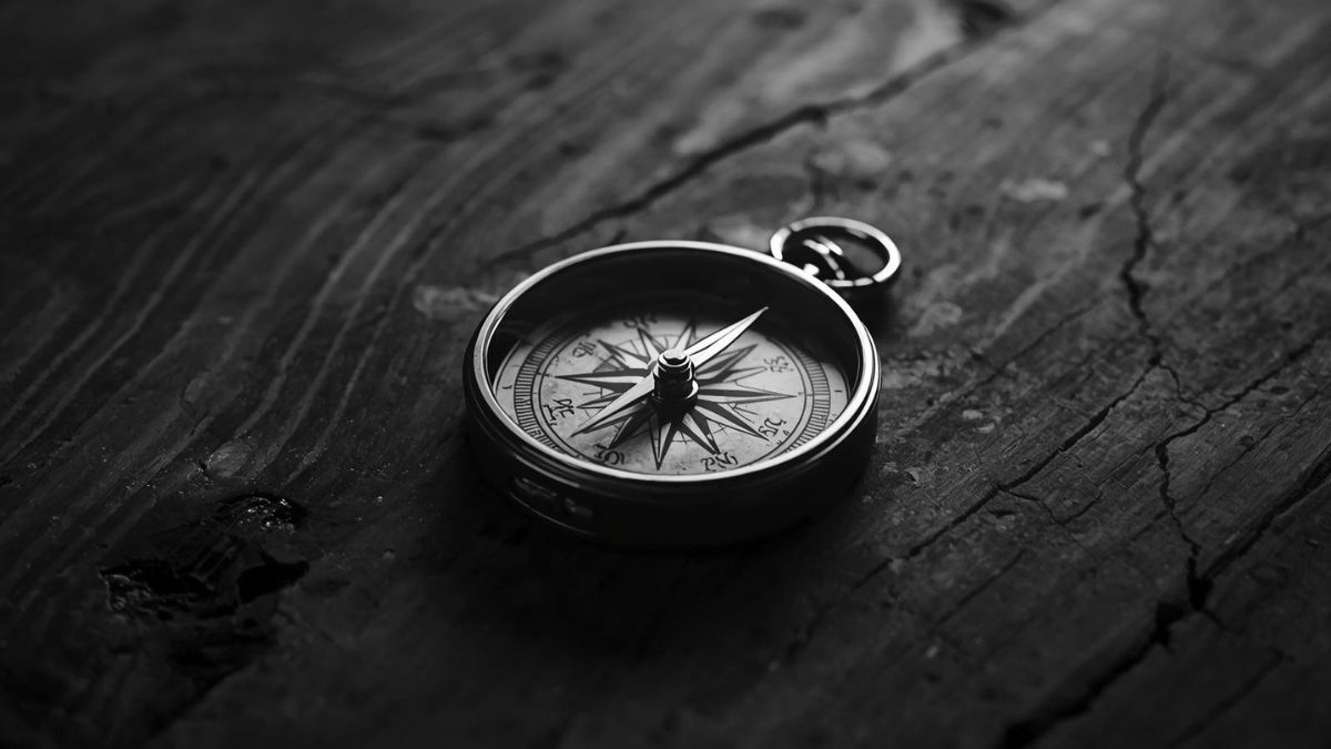 A vintage compass on a wooden table with the needle spinning, representing the confusion caused by gaslighting.
