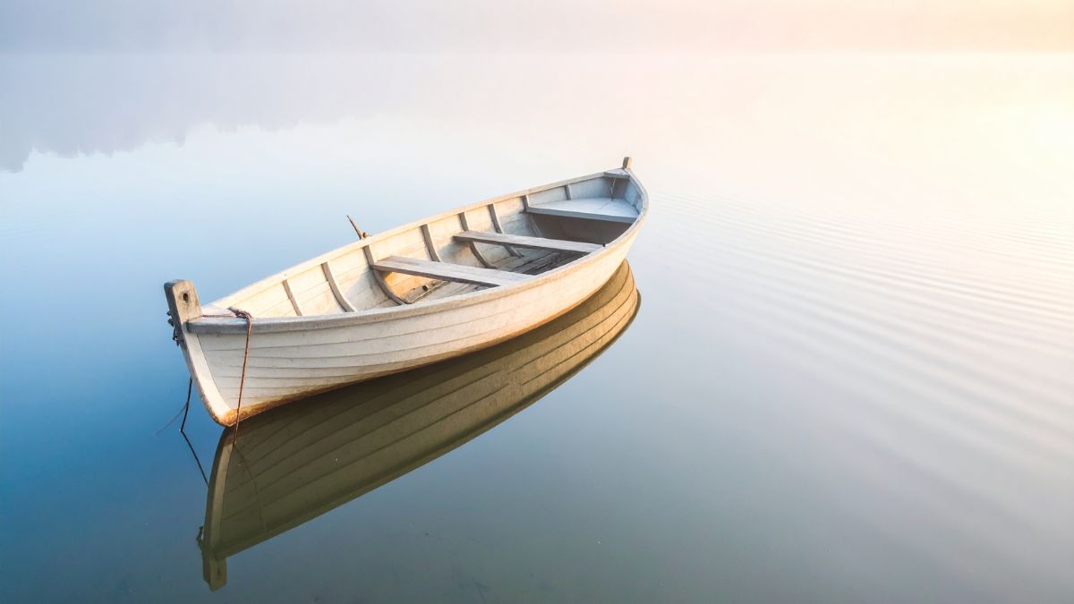 A solitary wooden boat floating on a misty lake representing the feeling of grief.