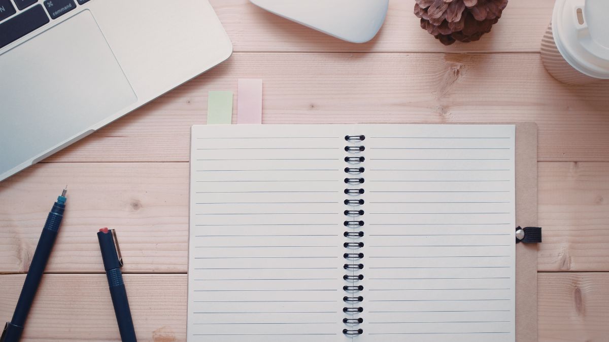 An open notebook on a desk in dim light, representing hesitation.