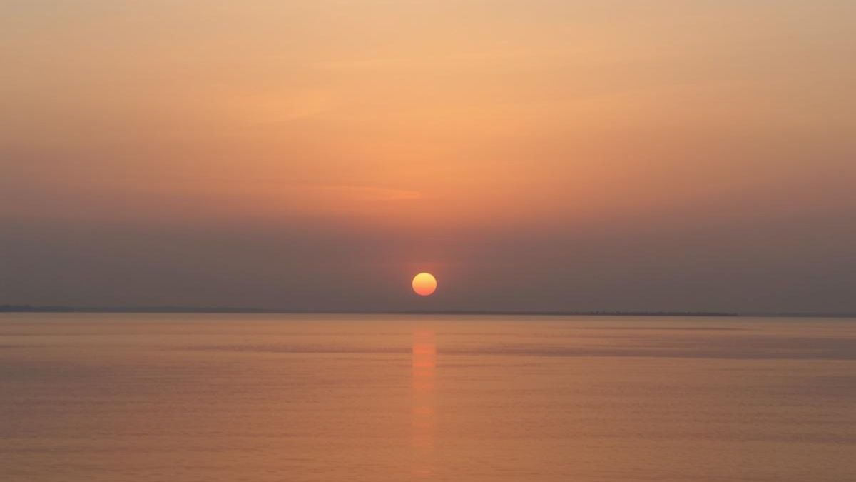 A peaceful sunrise over water representing the start of a fresh day and the body's natural wake cycle.