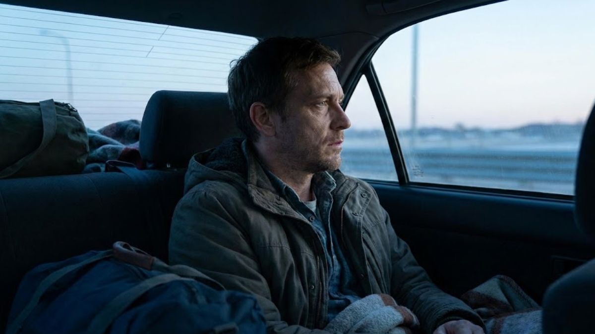 A man sitting in the back of a car at dawn, looking out the window, representing the hidden nature of homelessness.