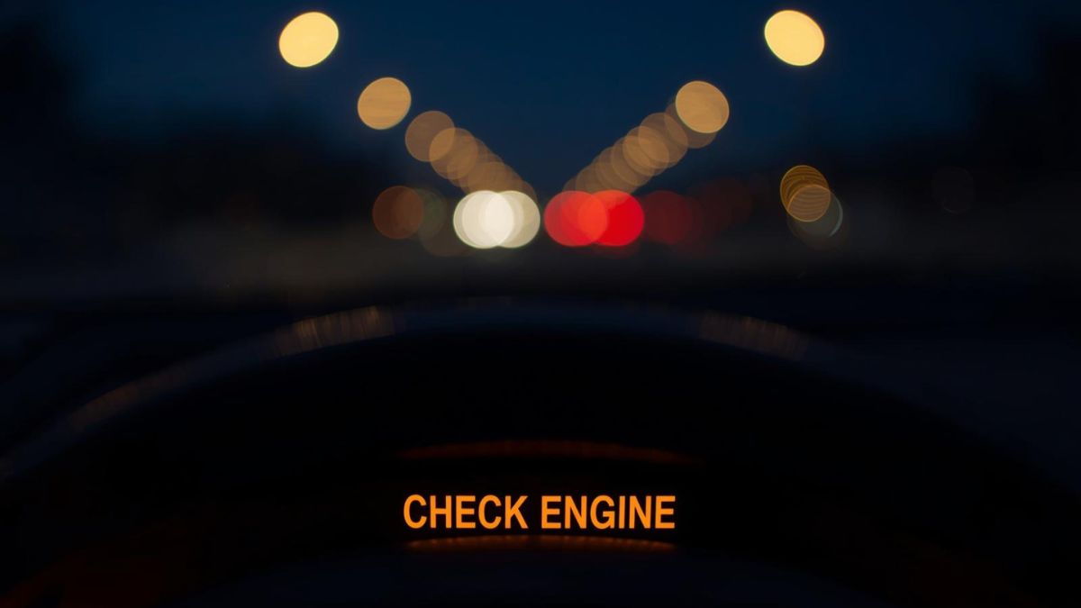 A car dashboard check engine light illuminating in the dark, symbolizing mental health warning signs.