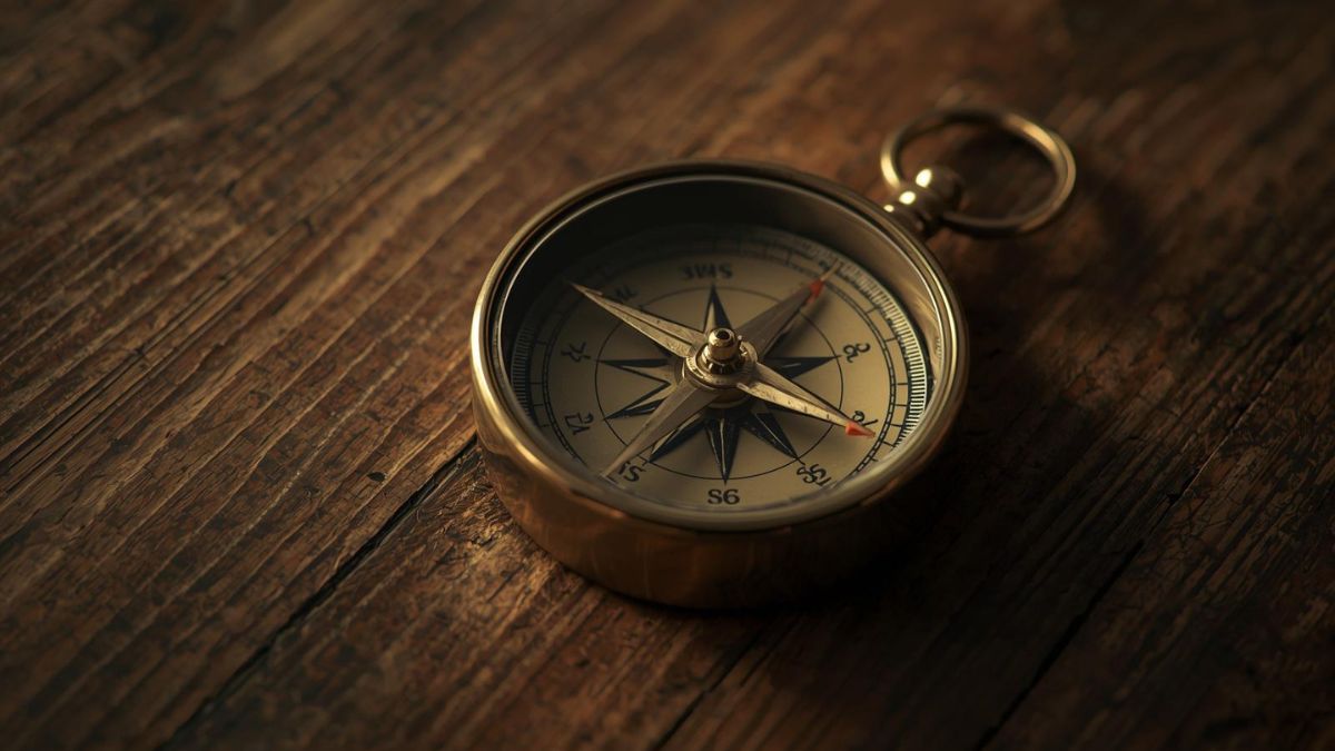 A compass with a spinning needle on a wooden table representing confusion.