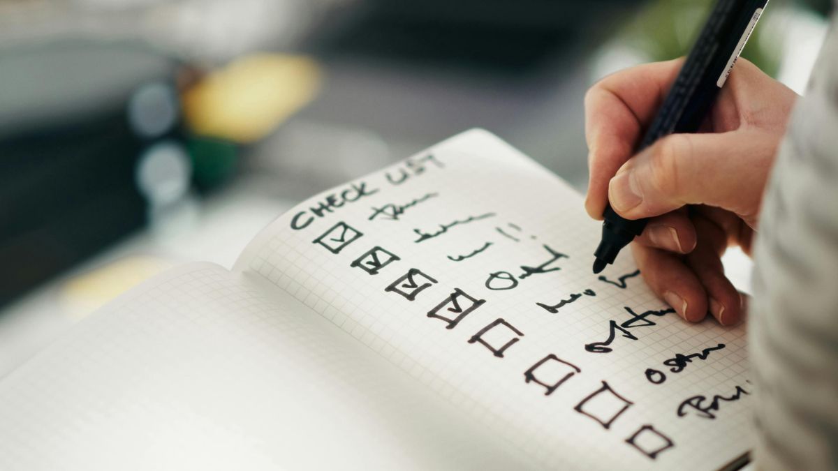 A person writing a shopping list in a notebook to plan for healthy eating.