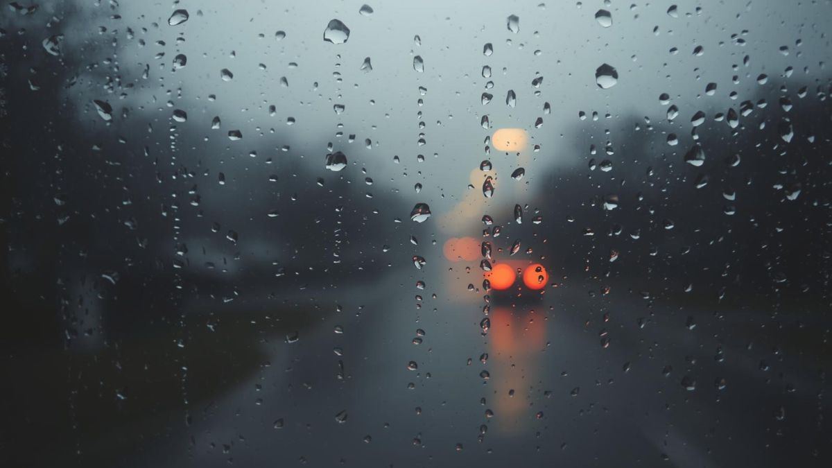 Raindrops on a window pane blurring the outside world, representing isolation and numbness.