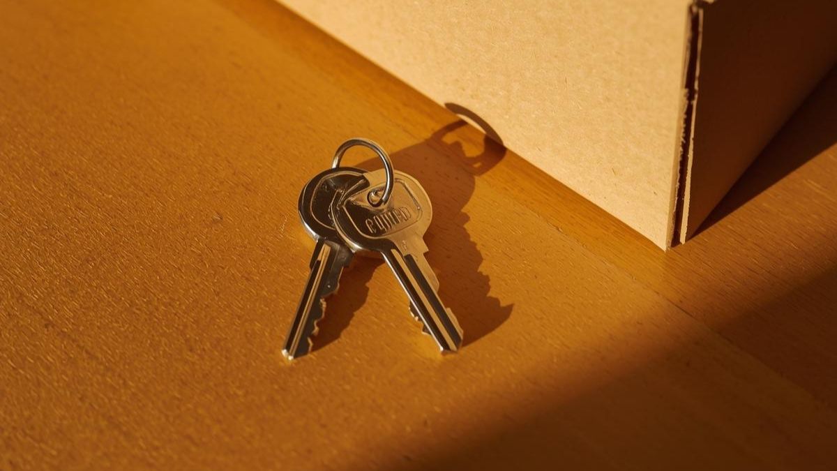 House keys on a table next to a packed box, symbolizing the end of a relationship and moving out.