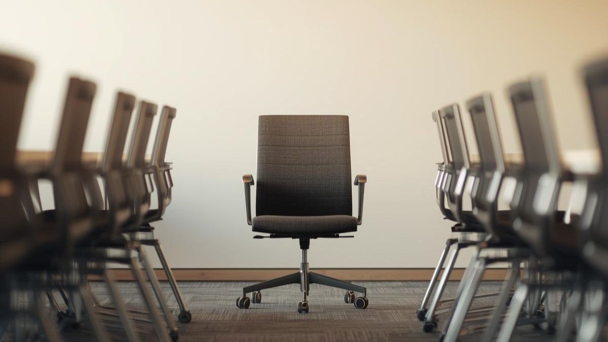 An empty chair separated from a group in an office setting, representing workplace bullying and exclusion.